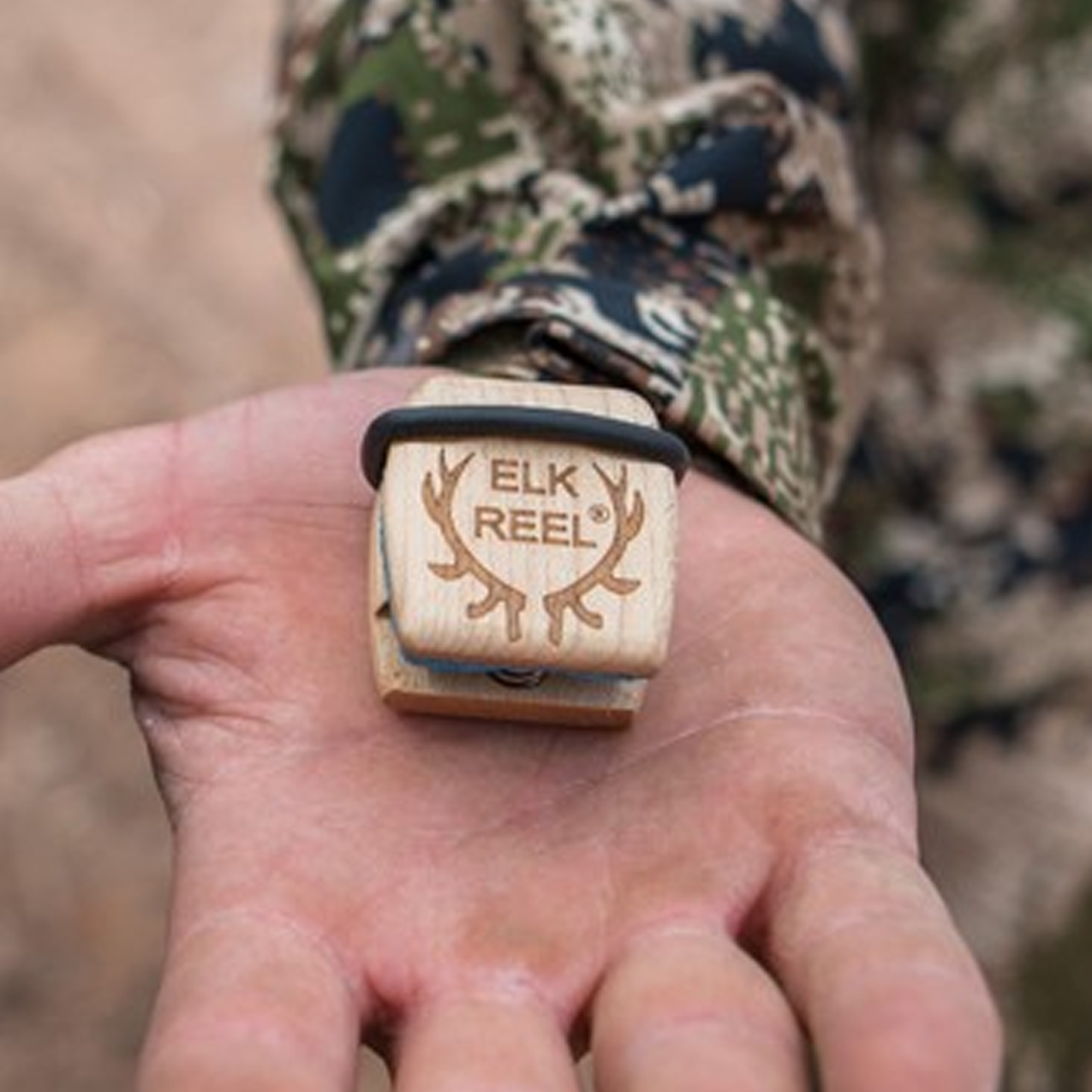 The Elk Reel classic call hardwood in a hunter's palm